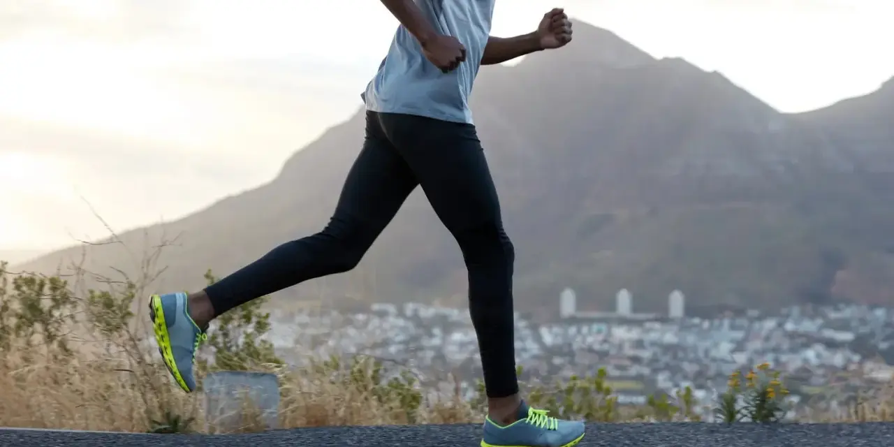 Un homme court sur une route, profitant d'un exercice cardio avec une vue sur la ville et les montagnes.