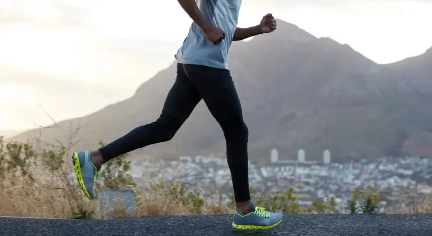 Un homme court sur une route, profitant d'un exercice cardio avec une vue sur la ville et les montagnes.