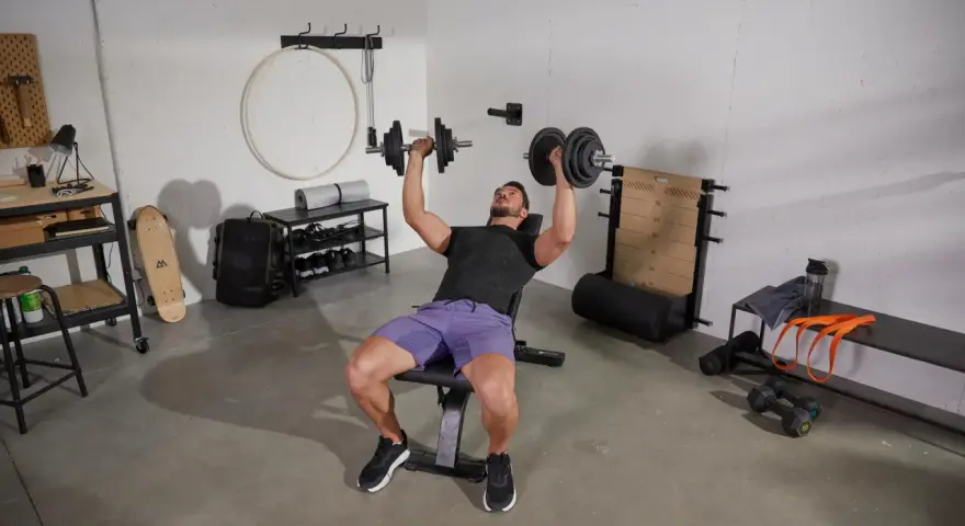 Homme faisant un exercice banc de musculation avec haltères.