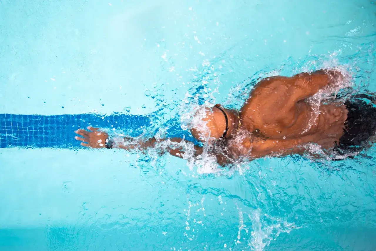 Un nageur effectue un exercice de natation en crawl, cr&eacute;ant des &eacute;claboussures d'eau bleues.