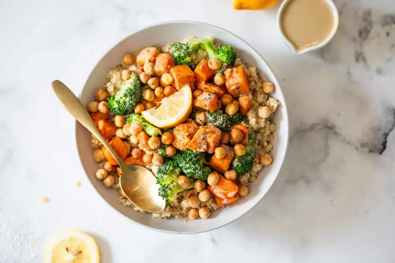 Un bol color&eacute; de quinoa, patates douces, brocolis et pois chiches, garni d'une tranche de citron. Une cuill&egrave;re dor&eacute;e invite &agrave; savourer, calmant la sensation de faim.