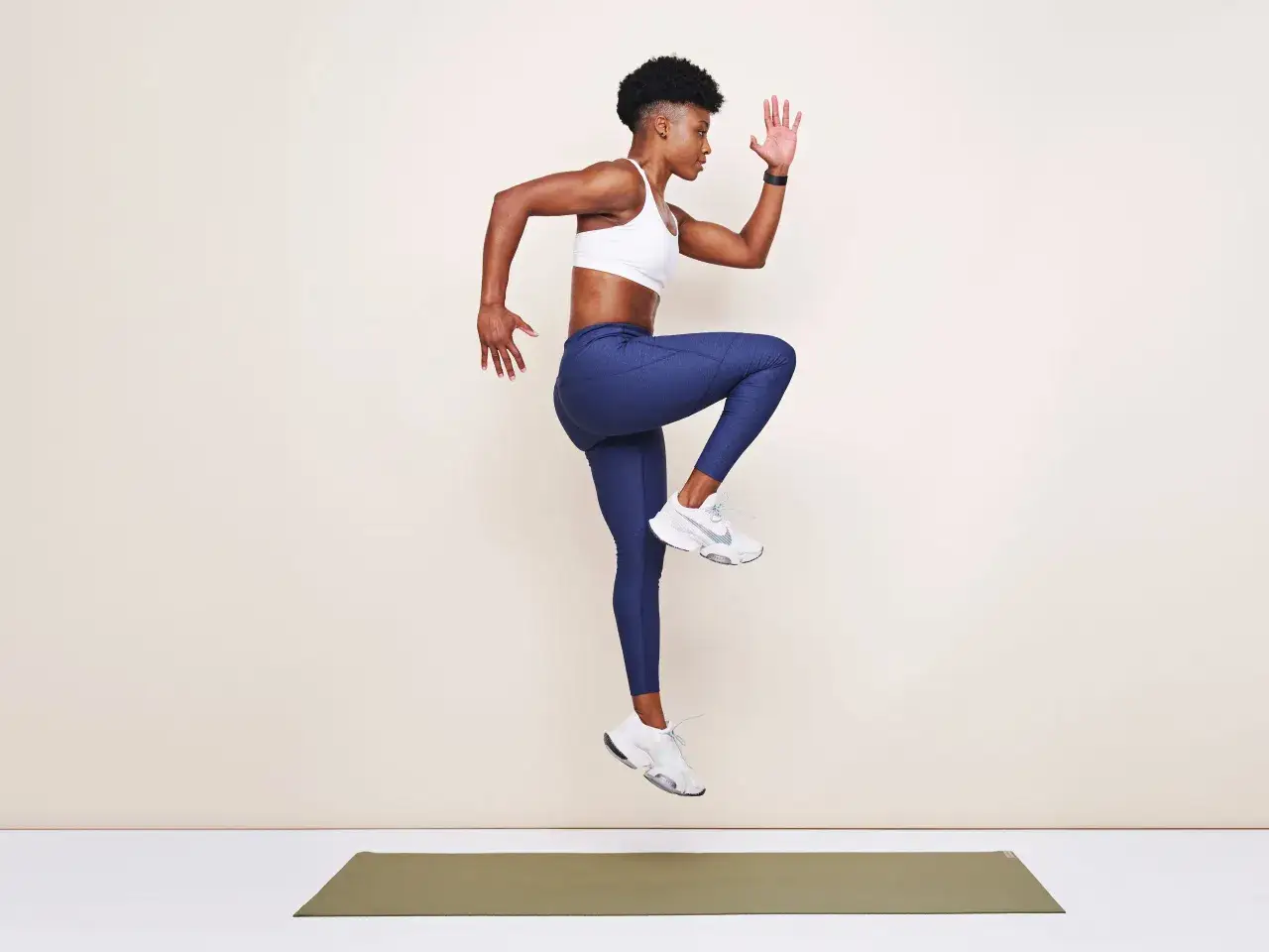 Femme en plein saut, genou lev&eacute;, bras tendus. Un exercice de pliom&eacute;trie dynamique pour exploser.
