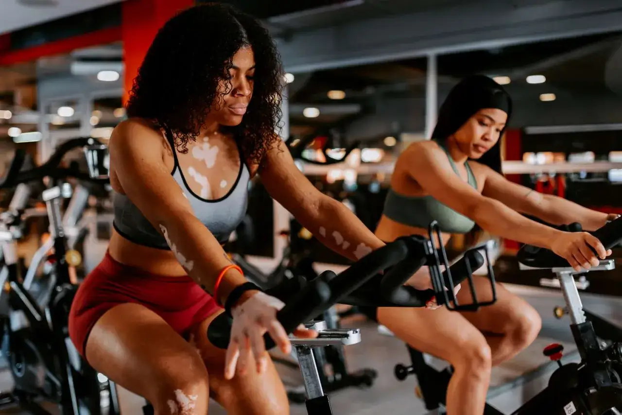 Deux femmes s'entra&icirc;nent sur des v&eacute;los d'appartement, profitant d'une s&eacute;ance de rpm sport intense.
