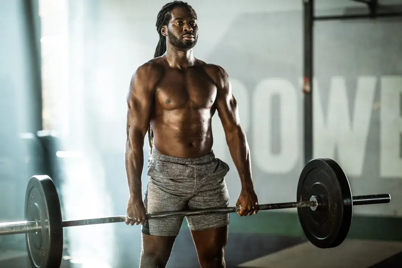 Un homme muscl&eacute;, transpirant, tient une barre charg&eacute;e. Il est la preuve qu'il est possible de prendre de la masse musculaire quand on est maigre.